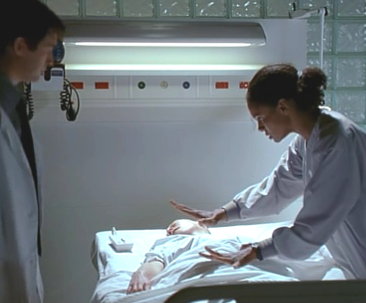 Susie allontana con un gesto l’assistente del professore (Jonathan M. Woodward), perché non tocchi il corpo di Vivian